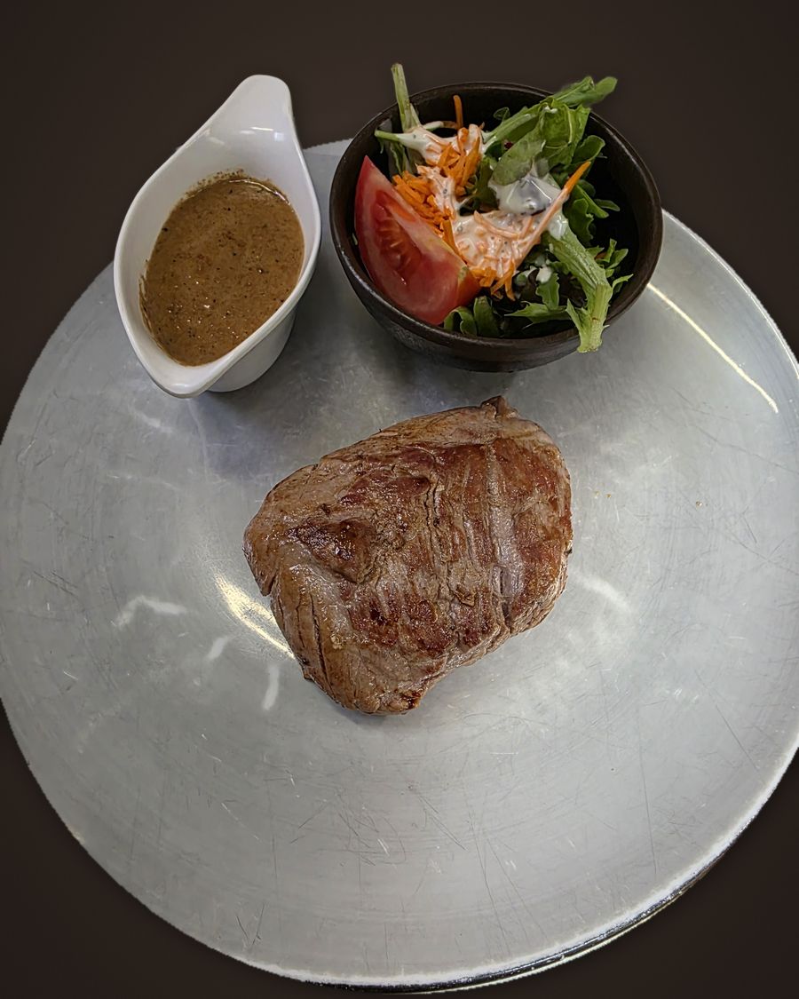 Steak with sauce and a side salad